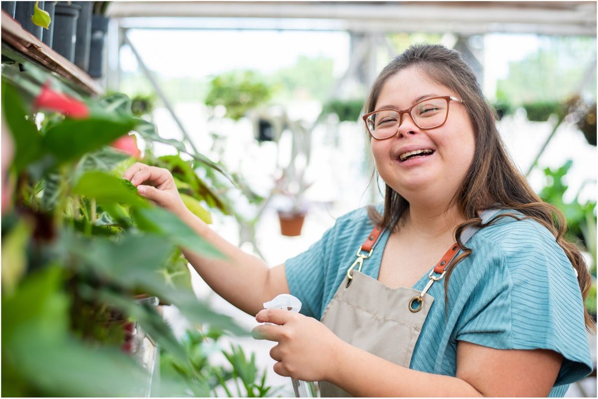 Young woman joyfully tending to plants in a greenhouse