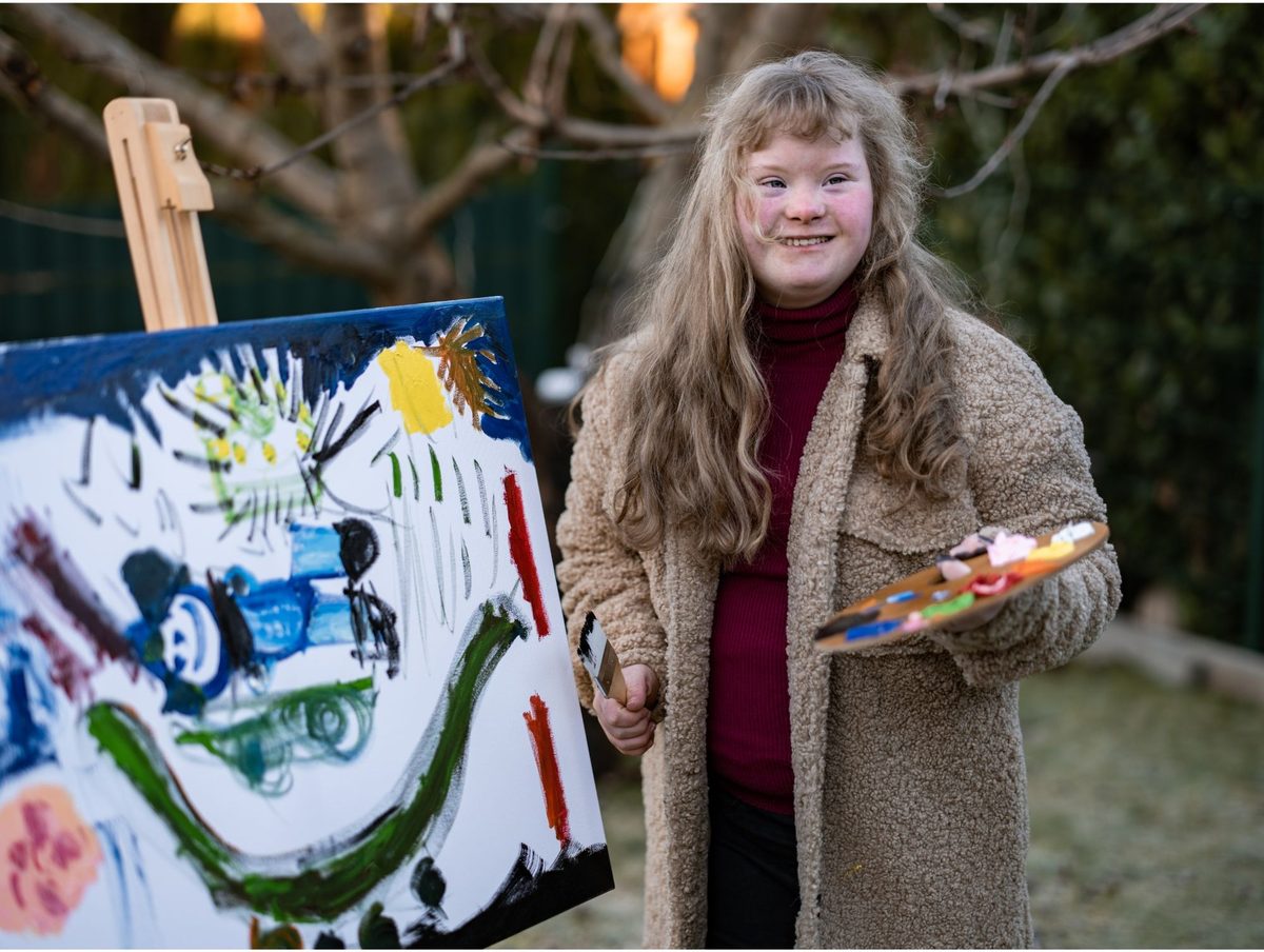 Young woman proudly showing her painting outdoors