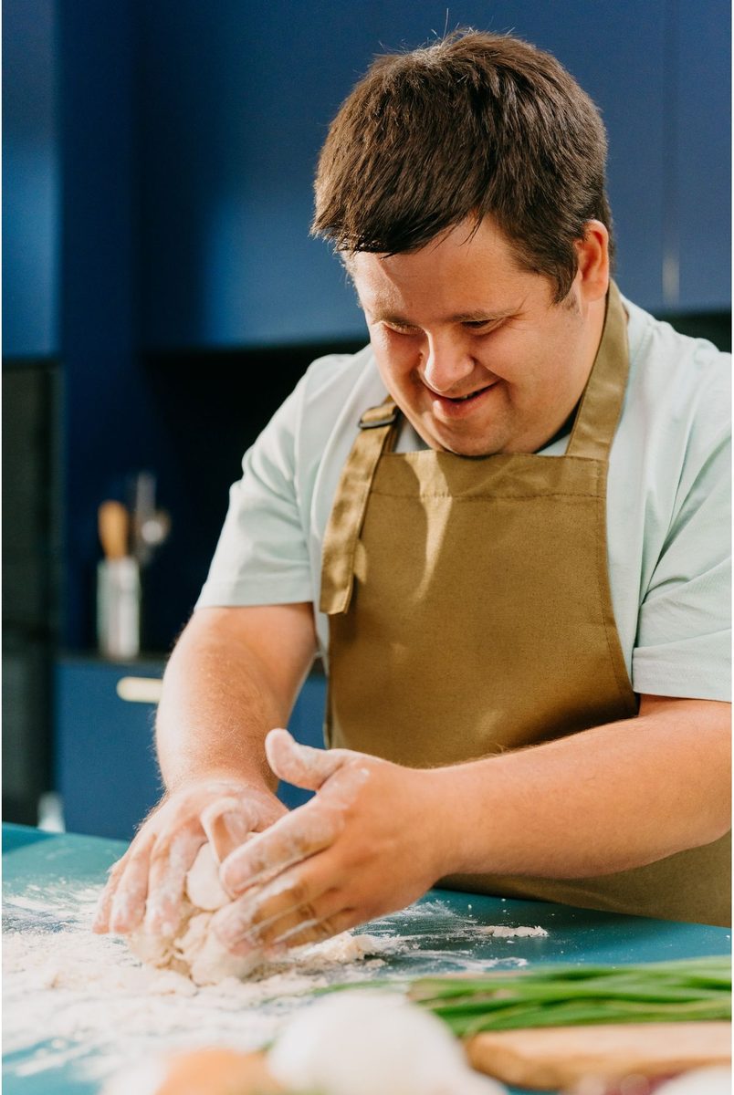 Man happily baking and kneading dough