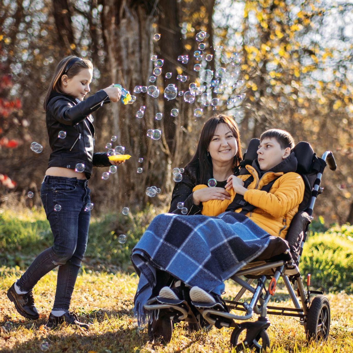Mother with child in wheelchair in autumn park